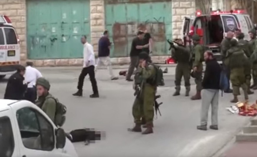 Der Soldat (mit dem erhobenen Gewehr) lädt seine Waffe durch. Der Palästinenser liegt regungslos und verletzt am Boden. Er hatte Israelis mit einem Messer angegriffen.