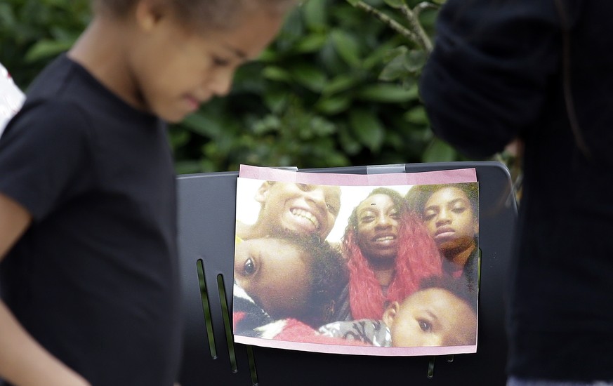 A neighbor girl walks past a memorial outside where a pregnant mother was shot and killed a day earlier at her apartment by police Monday, June 19, 2017, in Seattle. A cousin of a mother who was shot  ...