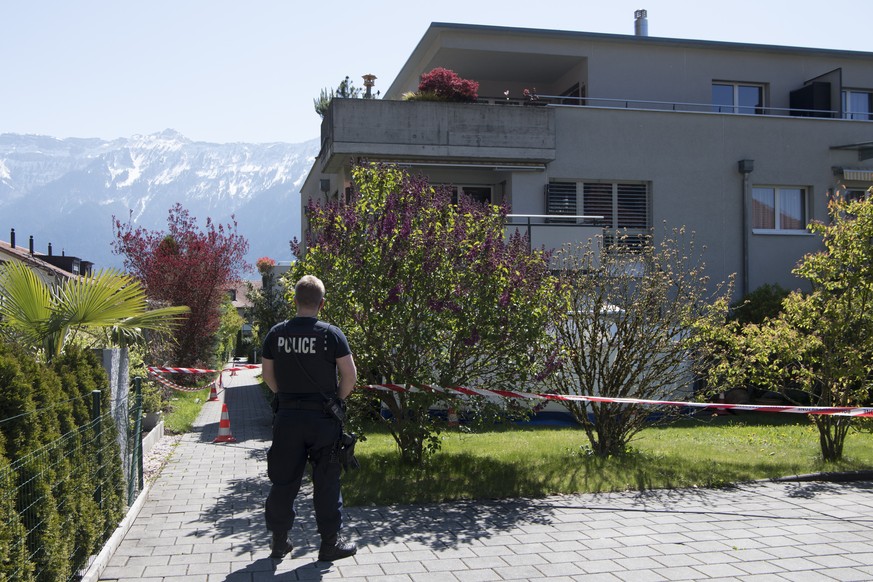 Ein Polizist steht vor einem Absperrband vor einer Wohnung, am Samstag, 22. April 2017, in Unterseen. Zwei Maenner und eine Frau sind im bernischen Unterseen am fruehen Samstagmorgen Opfer eines mutma ...