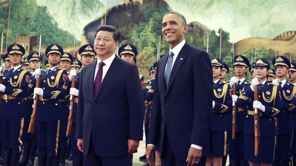 FILE - In this Nov. 12, 2014 file photo, U.S. President Barack Obama, right, smiles after a group of children waved flags and flowers to cheer him during a welcome ceremony with Chinese President Xi J ...