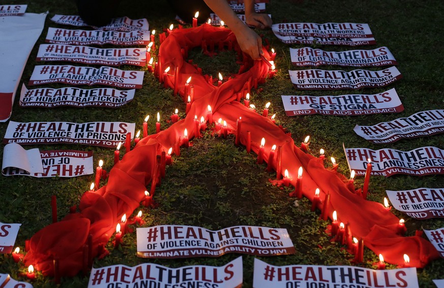 FILE - In this Dec.1, 2016 file photo, an HIV-positive Filipino lights candles around an AIDS symbol as he participates in an event in observance of World AIDS Day in Quezon city, Philippines. For the ...