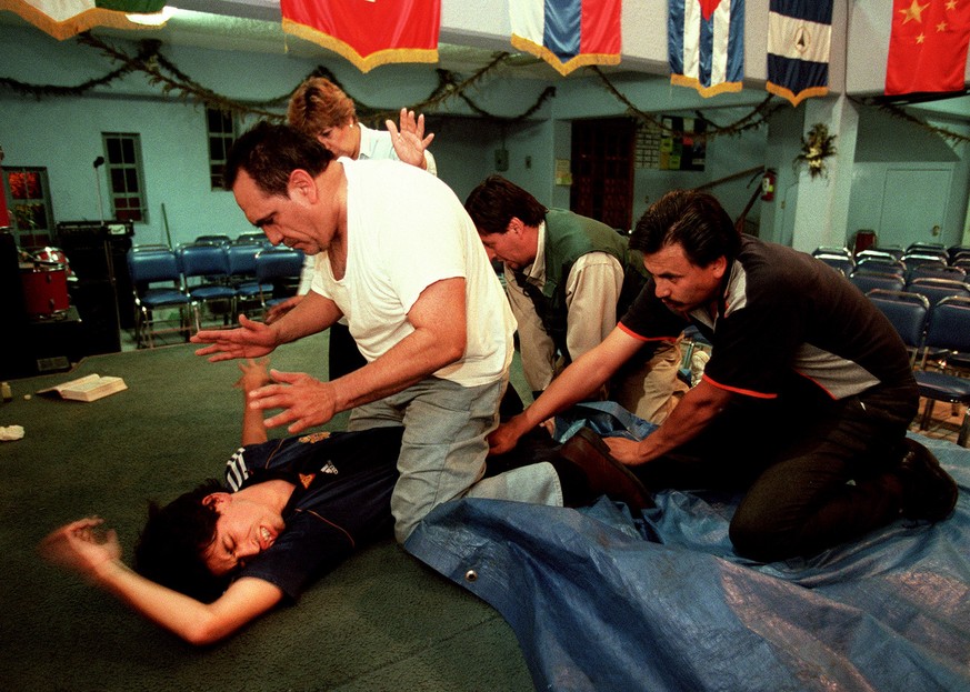 Protestant priest Pedro Alvarez prays while sitting above Arturo Sanchez, as others hold Sanchez down, during an exorcism at a Protestant church in Mexico City, October 28, 2000. Sanchez, underwent th ...