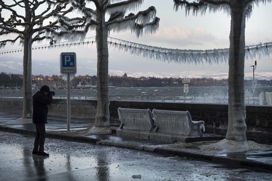 Une personne photographie une banc ensevelie par la glace se formant suite au vent fort au bord du lac Leman ce mardi 17 janvier 2017 a Versoix dans le canton de Geneve. (KEYSTONE/Jean-Christophe Bott ...