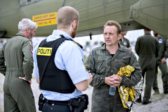 epa06137906 Danish submarine owner and inventor Peter Madsen (R) speaks to a Danish policeman after landing with the help of the Danish defense in Dragor Harbor south of Copenhagen, Denmark, 11 August ...