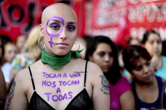 A woman with text written on her chest that reads in Spanish reading &quot;If you touch one of us, you touch us all,&quot; attends a demonstration to commemorate International Women&#039;s Day in Buen ...