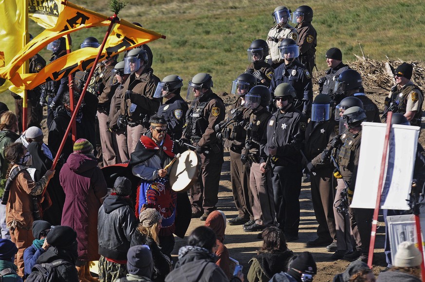 A person with a hand drum paces between law enforcement officers and a line of protesters along North Dakota Highway 6, south of St. Anthony, N.D., Monday, Oct. 10, 2016. The U.S. Army Corps of Engine ...