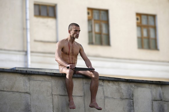 Petr Pavlensky sitzt mit abgeschnittenem Ohrläppchen auf der Mauer eines Psychiatrie-Zentrums.&nbsp;
