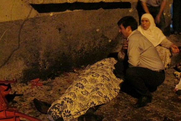 A man and a woman mourn next to a body of one the victims of a blast targeting a wedding ceremony in the southern Turkish city of Gaziantep, Turkey, August 20, 2016. Ihlas News Agency via REUTERS TURK ...