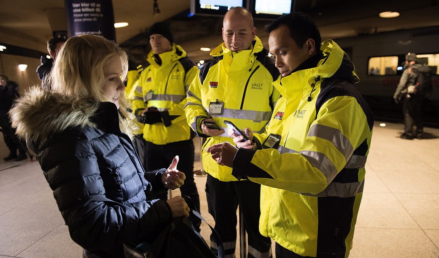 Sicherheitspersonal überprüft im dänischen Kastrup die Identitätskarte einer Pendlerin.