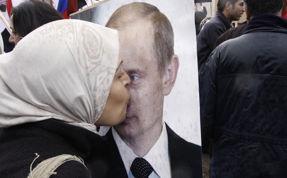 Eine Assad-Anhängerin küsst ein Bild von Wladimir Putin.