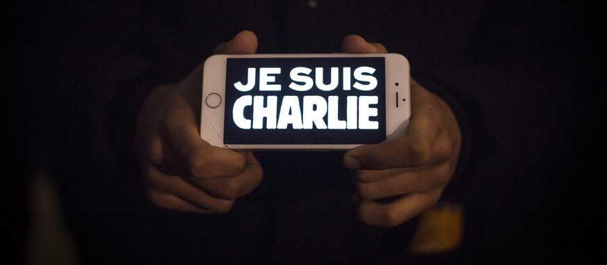 LONDON, ENGLAND - JANUARY 07: A man holds a phone displaying &quot;Je suis Charlie&quot; (I am Charlie) during a vigil in Trafalgar Square for victims of the terrorist attack in Paris on January 7, 20 ...