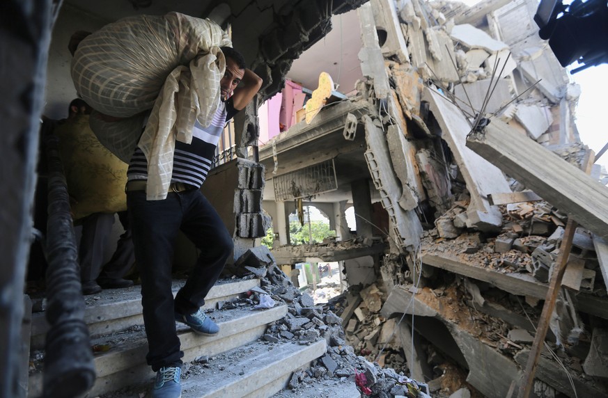 Palästinenser tragen Habseligkeiten aus einem von israelischen Bomben zerstörten Haus in Gaza City.