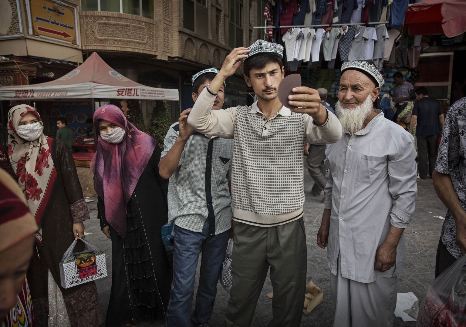 Anprobe einer neuen Mütze: Uigurische Männer sind selten ohne Kopfbedeckung anzutreffen.&nbsp;
