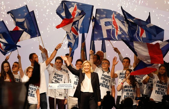 Frances far-right National Front president Marine Le Pen, center, surrounded by members, waves to supporters after her speech during their meeting in Marseille, southern France, Saturday, Sep. 6, 201 ...