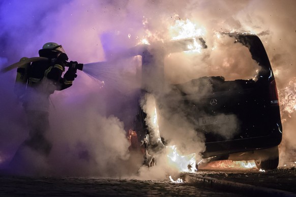 epaselect epa06074630 Firefighters extinguish the fire of a burning car during riots at the G20 summit in Hamburg, Germany, 08 July 2017. The G20 Summit (or G-20 or Group of Twenty) is an internationa ...