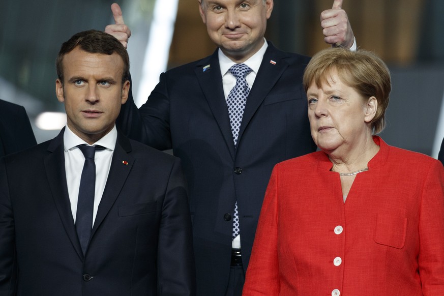 Polish President Andrzej Duda gives a thumbs-up behind French President Emmanuel Macron and German Chancellor Angela Merkel as hey pose for a group photo with NATO leaders at the new NATO headquarters ...