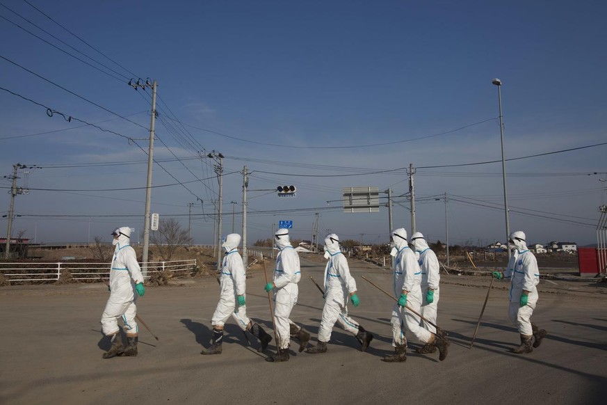 In this Thursday April 7, 2011 photo, Japanese police wearing protective radiation suits search for the bodies of victims of the tsunami in the Odaka area of Minamisoma, inside the deserted evacuation ...