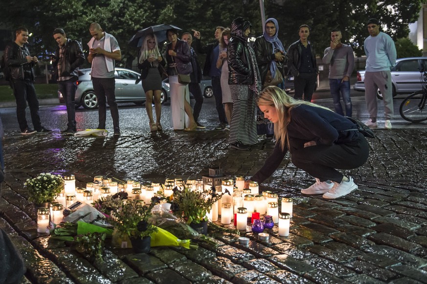 epa06150590 People place candles and flowers to the site where one person was stabbed to death on the Market Square in Turku, Finland, 18 August 2017. According to police reports on 18 August, two peo ...