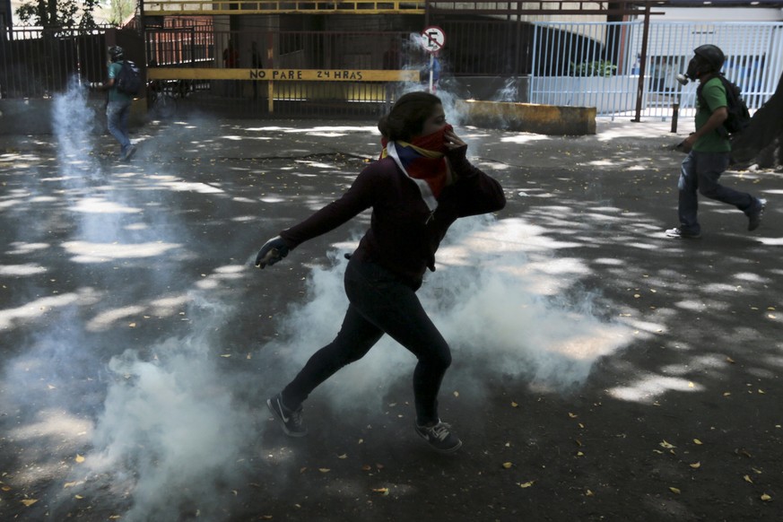 A demonstrator throws back a tear gas canister during clashes with security forces at a protest in Caracas, Venezuela, Wednesday, April 19, 2017. Venezuelan National Guard members are deploying tear g ...