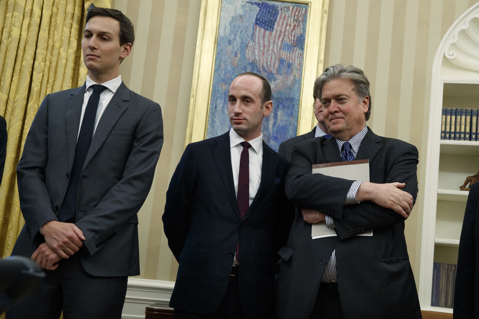 From left, Senior Adviser Jared Kushner, policy adviser Stephen Miller, and chief strategist Steve Bannon watches as President Donald Trump signs an executive order to withdraw the U.S. from the 12-na ...
