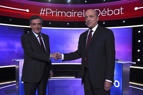 French politicians Alain Juppe (R) and Francois Fillon shake hands as they arrive to attend the third prime-time televised debate as they campaign in the second round for the French center-right presi ...