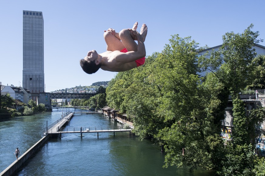 Ein Mann springt bei rund 30 Grad zum Sommerbeginn in die kalte Limmat, im Hintergrund das noch leere Schwimmbad Unterer Letten, aufgenommen am Mittwoch, 22. Juni 2016 in Zuerich. (KEYSTONE/Ennio Lean ...