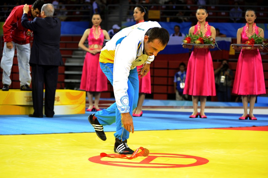 In this picture made available Friday, Aug. 15, 2008, Greco-Roman men&#039;s 74-84Kg bronze medalist, Sweden&#039;s Ara Abrahamian leaves his medal on the mat during the medal ceremony to protest agai ...