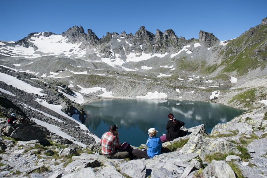 Wanderer machen Rast bei der Wildseeluggen mit Blick auf den Wildsee, auf der Fuenf Seen Wanderung, in Wangs-Pizol, am Mittwoch, 16. Juli 2014. (KEYSTONE/Gian Ehrenzeller)