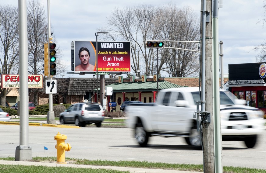 In this Thursday, April 6, 2017 photo, vehicles drive by an electronic billboard in Janesville, Wis., showing a wanted sign for Joseph Jakubowski. A manhunt was underway Friday for Jakubowski suspecte ...