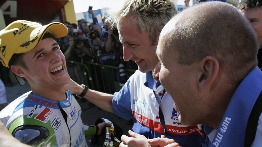 Newly crowned 125cc World Champion, Swiss motorcycle pilot Thomas Luethi from Czech Elit team, left, celebrates with his team owner Daniel Epp from Switzerland, right, and his riding coach Andy Ibbott ...