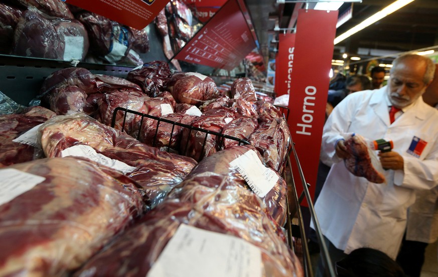 A member of the Public Health Surveillance Agency measures the temperature where the products are exposed at a supermarket after the Chilean government suspended all meat and poultry imports from Braz ...