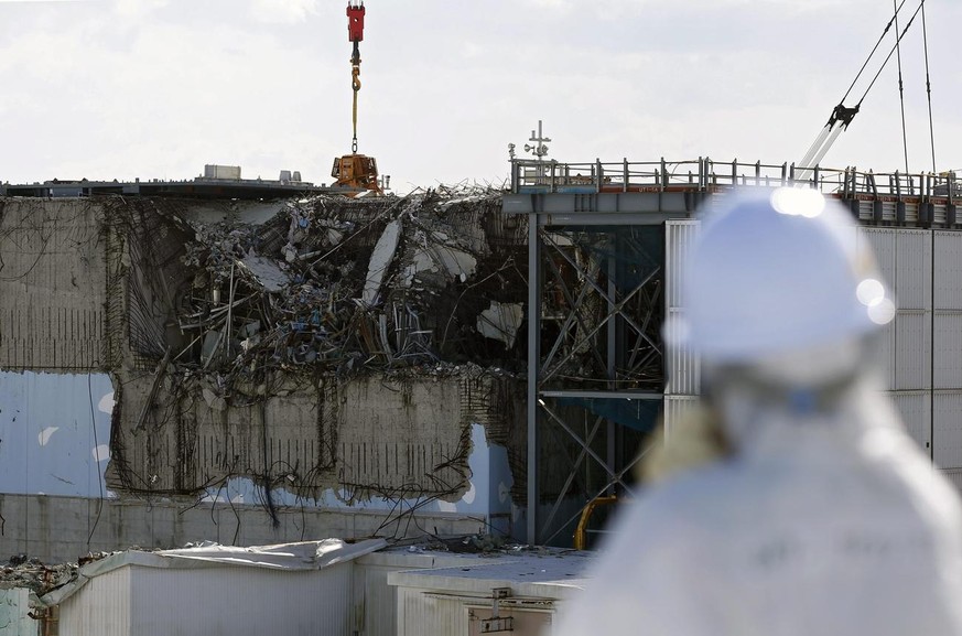 epa05152388 A member of the media wearing a protective suit and a mask looks at the No. 3 reactor building at Tokyo Electric Power Co&#039;s (TEPCO) tsunami-crippled Fukushima Daiichi nuclear power pl ...