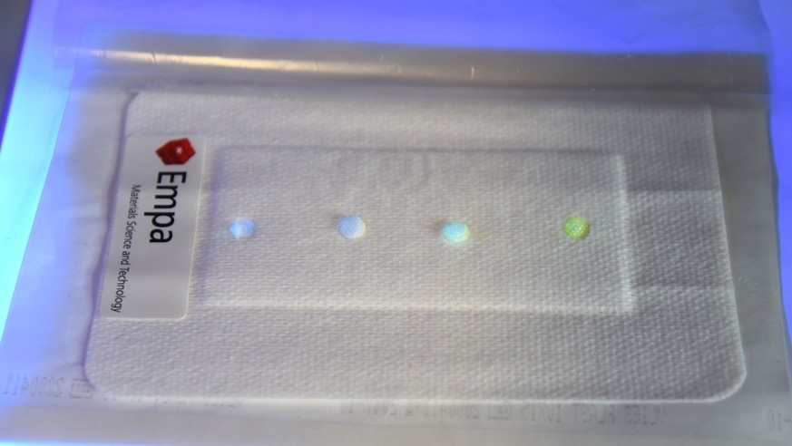 Prototyp des Sensor-Pflasters: Im UV-Licht zeigt es den PH-Wert der Wunde an.