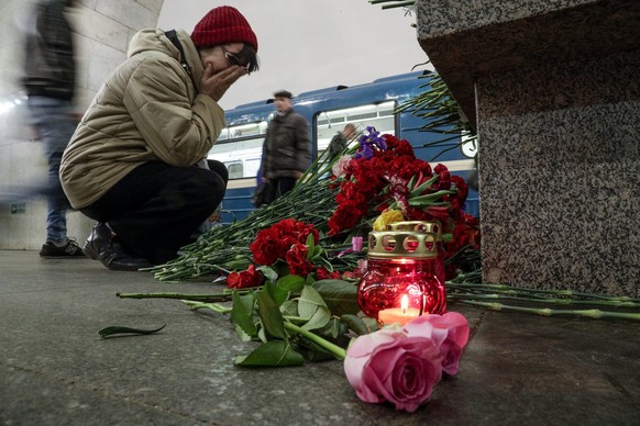 A woman reacts as she lays flowers at a symbolic memorial at Tekhnologichesky Institute subway station in St. Petersburg, Russia, Tuesday, April 4, 2017. A bomb blast tore through a subway train deep  ...