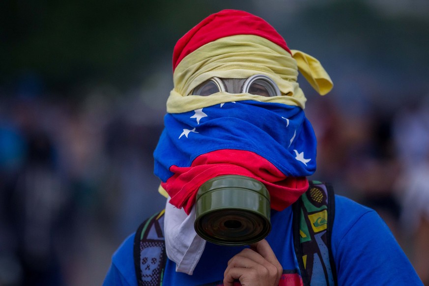 epaselect epa05902083 A protester wearing a gas mask is seen during clashes with the Venezuelan National Guard (GNB) in Caracas, Venezuela, on 10 April 2017. The security forces of Venezuela disperse, ...