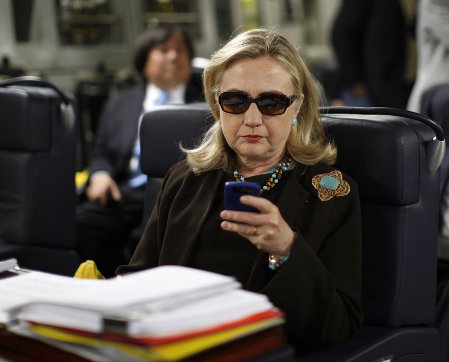 FILE - In this Oct. 18, 2011, file photo, then-Secretary of State Hillary Rodham Clinton checks her Blackberry from a desk inside a C-17 military plane upon her departure from Malta, in the Mediterran ...