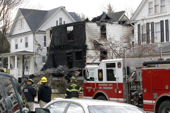 Fire officials stand at the scene of an early morning house fire in Baltimore, Thursday, Jan. 12, 2017. A woman and several children in the house were injured and multiple other children in the family ...