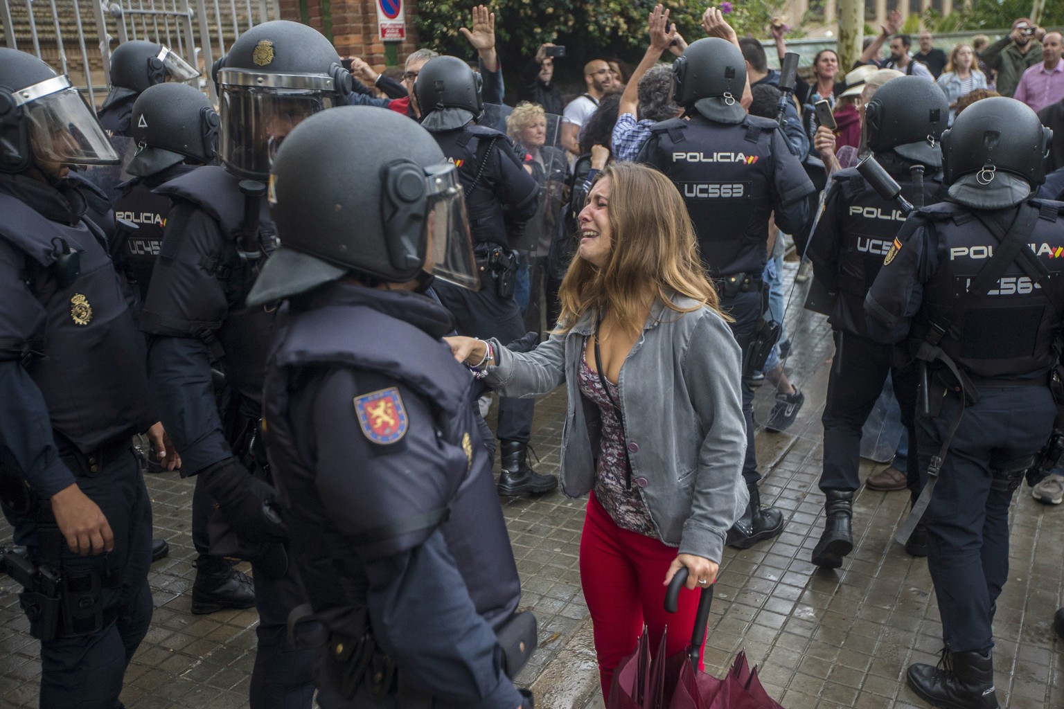 epa06238136 A woman address an officer of National Police outside a polling center set at Can Vilumara Secondary School in L&#039;Hospitalet Llobregat, Barcelona, Catalonia, northeastern Spain, on 01  ...