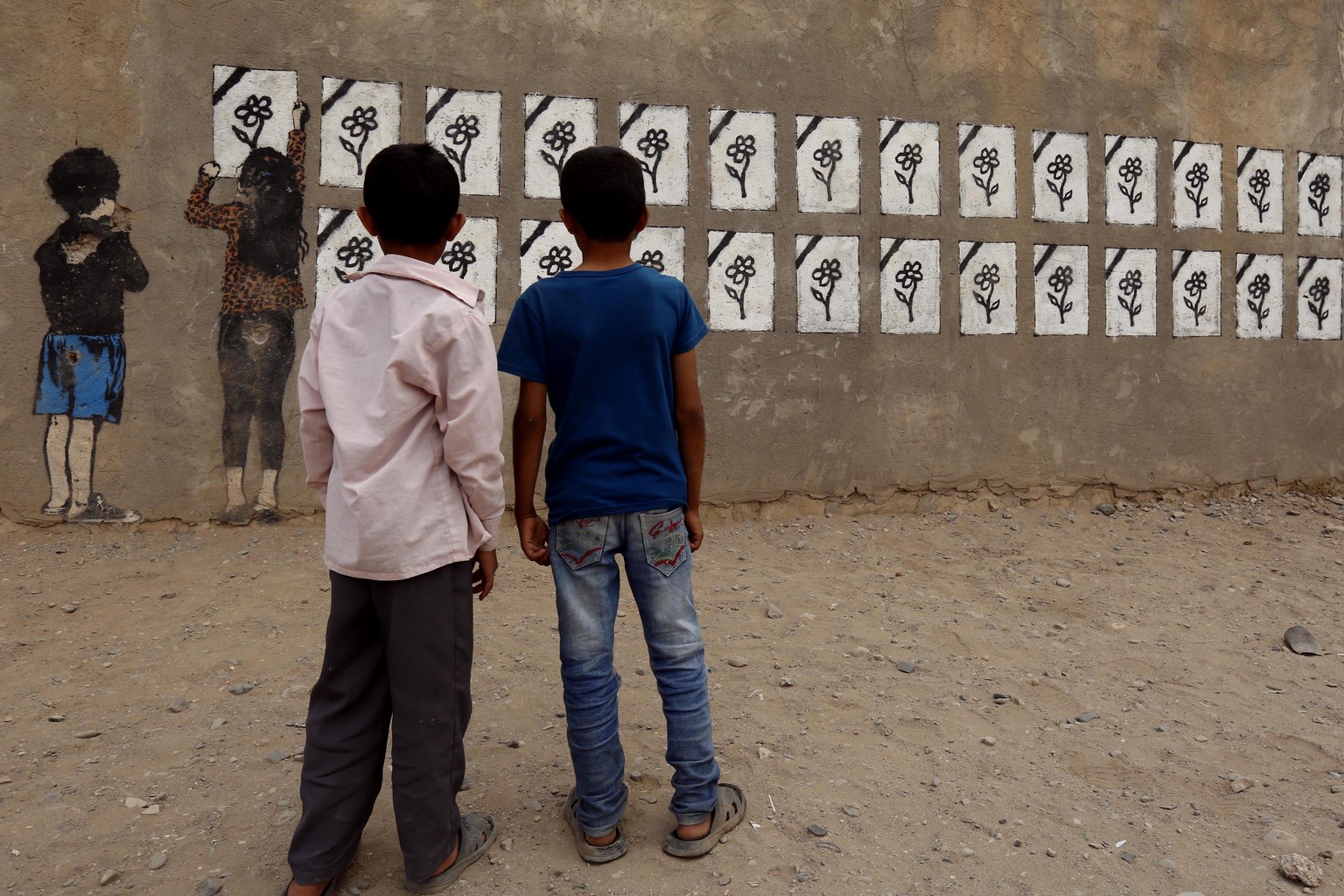 epaselect epa05870201 Yemeni boys look at graffiti on a wall commemorating the victims of Saudi-led airstrikes on buildings two years ago, in Sana&#039;a, Yemen, 25 March 2017. On 26 March 2015, the S ...