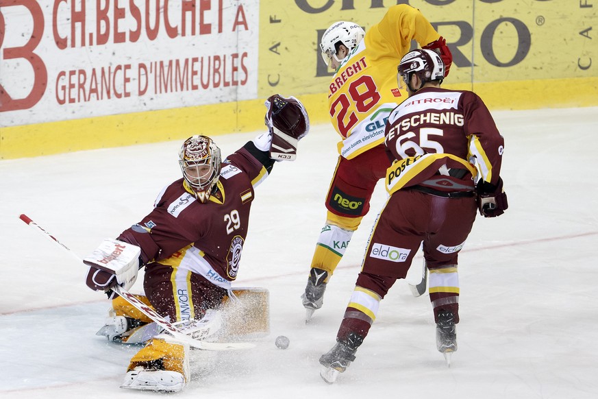 Geneve-Servette&#039;s goaltender Robert Mayer, left, saves a puck past Tigers&#039; center Yannick-Lennart Albrecht, center, and Geneve-Servette&#039;s defender Will Petschenig, of Canada, right, dur ...