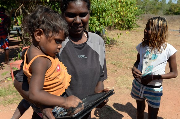 epa04297630 18-month old Nevaeh Dickson plays with an iPad held by her mother Tara Black, in the aboriginal community of Peppimenarti, about 320km south-west of Darwin, Australia, 04 July 2014. Peppim ...