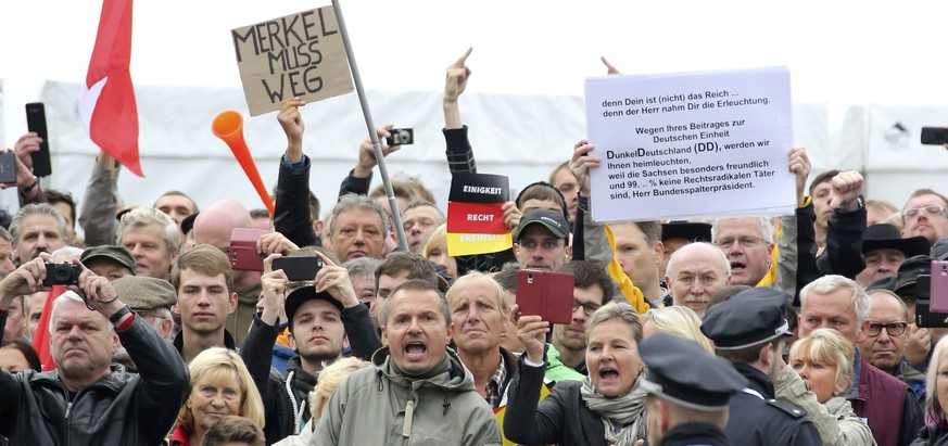 Police watches protestors holding a placard &quot;Merkel must go&quot; during celebrations marking the German Unification Day in Dresden, Germany, October 3, 2016. REUTERS/Fabrizio Bensch