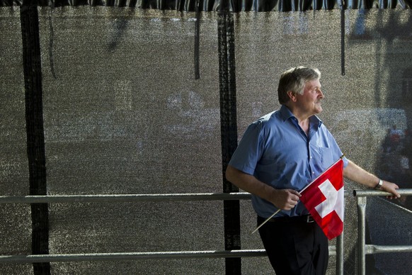 Member of the Parliament and of the SVP, Hans Fehr from Zurich, holding a Swiss flag, watches the crowd during the Familienfest on the Bundesplatz square, an election event of the rightist Swiss peopl ...