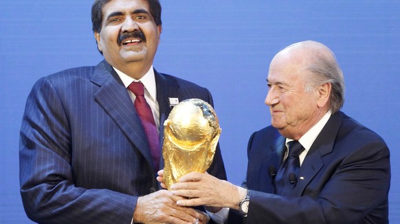FILE- In this Thursday, Dec. 2, 2010 file photo, Sheikh Hamad bin Khalifa Al-Thani, Emir of Qatar, left, gets the World Cup trophy by FIFA President Joseph Blatter, right, after the announcement of Qa ...