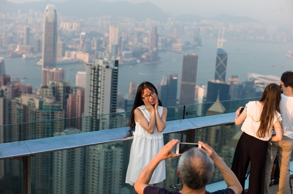 epa07012156 A woman poses for photographs on a panoramic deck overlooking Victoria Harbour in Hong Kong, China, 11 September 2018. Hong Kong Observatory raised the typhoon signal No 1 as Tropical Stor ...