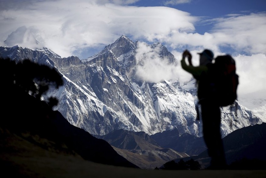 A tourist is silhouetted as he takes pictures of Mount Nuptse (C) as Mount Everest (L) is covered with clouds in Solukhumbu district, also known as the Everest region, in this picture taken November 3 ...