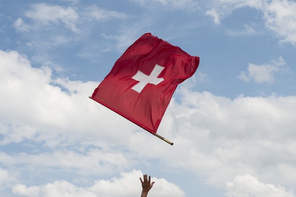 Ein Fahnenschwinger greift nach der Schweizer Fahne am 100. St. Galler Kantonalschwingfest am 25. Mai 2014 in Gossau. (KEYSTONE/Ennio Leanza)