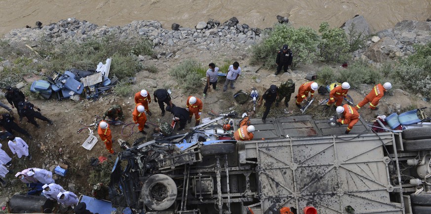 Rettungskräfte machen sich am verunfallten Bus im Tibet zu schaffen.