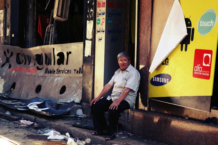 Ein Mann sitzt vor einem Laden, der durch die zwei Selbstmordattentäter im südlichen Beirut zerstört wurde.&nbsp;
