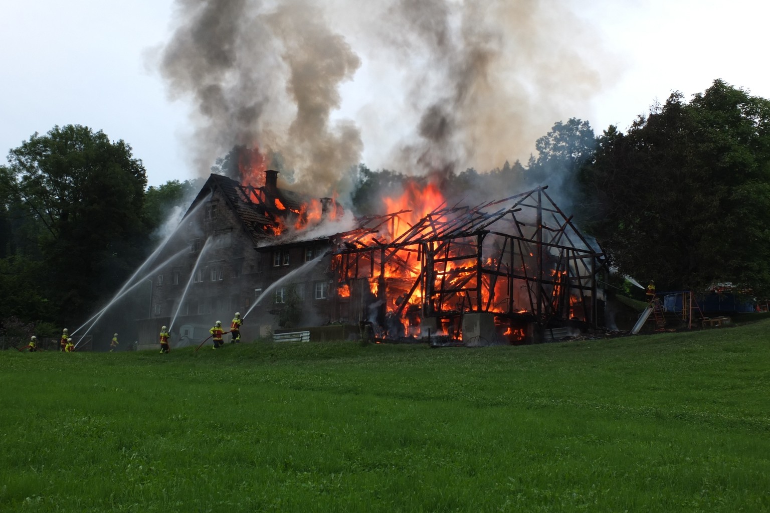 Feuerwehrleute versuchen den Brand in Hoffeld zu löschen, das Bauernhaus wird jedoch komplett zerstört.